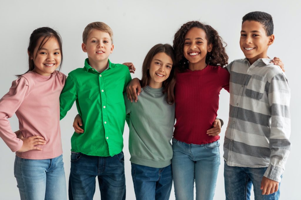 Cheerful Multicultural Preteen Kids Standing Posing Together Over Gray Background
