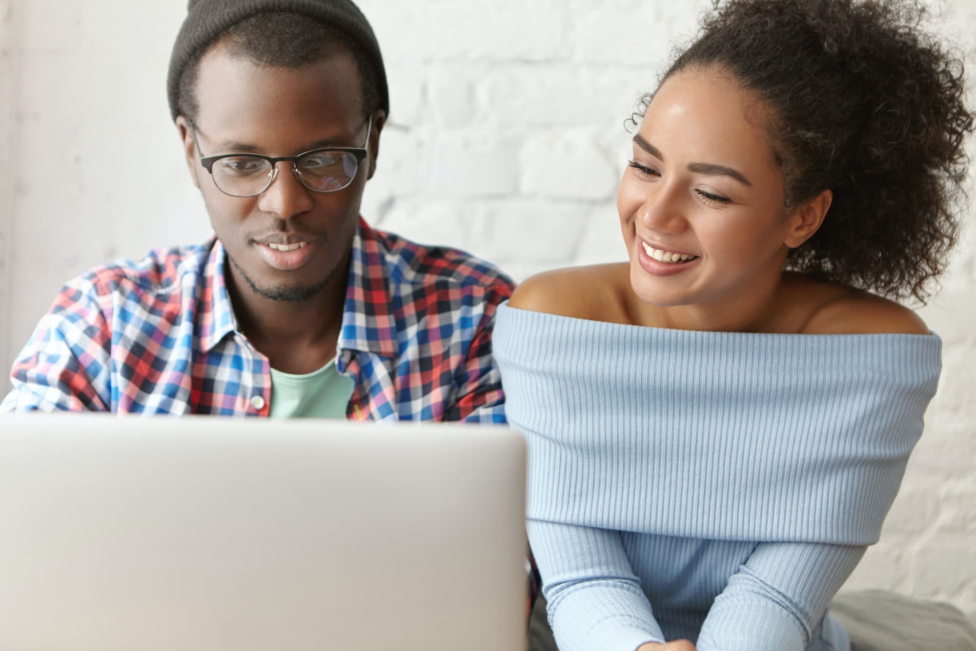People, relationships and technologies concept. Beautiful happy African American couple using laptop